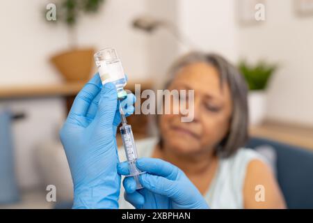 Eine junge männliche Krankenschwester bereitet eine Injektion für eine ältere weibliche Frau vor Stockfoto