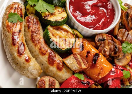Gegrillte Weißwürste Weisswurst, gegrillte gelbe und rote Paprika, Zucchini und Pilze mit Ketchup auf weißer Platte, Nahaufnahme, niederländischer Blickwinkel Stockfoto