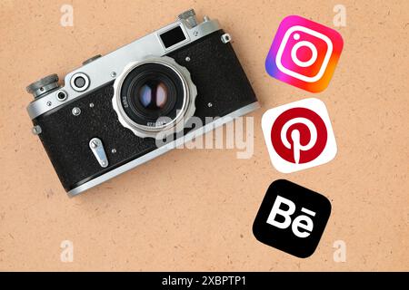 Retro-Fotokamera mit Social-Media-Symbolen, wie Instagram, Pinterest und Behance, auf einem alten Papierhintergrund Stockfoto