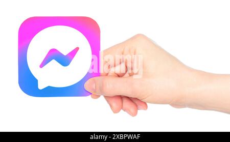 Die Hand hält das Symbol der mobilen Facebook Messenger App auf Papier auf einem transparenten Hintergrund. Facebook Messenger ist eine firmeneigene Instant Messaging-App in den USA Stockfoto