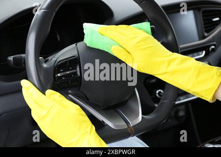 Frau, die das Lenkrad mit Lappen im Auto reinigt, Nahaufnahme Stockfoto