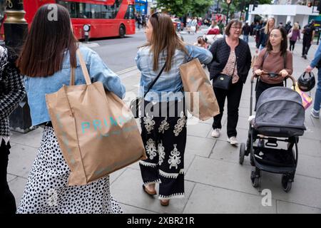 Käufer und Besucher auf der Oxford Street mit Einkaufstaschen am 9. Juni 2024 in London, Großbritannien. Die Oxford Street ist ein bedeutendes Einkaufszentrum im West End der Hauptstadt und ist Europas geschäftigste Einkaufsstraße mit rund einer halben Million Besuchern der rund 300 Geschäfte, von denen die meisten Mode- und High Street-Bekleidungsgeschäfte sind. Stockfoto