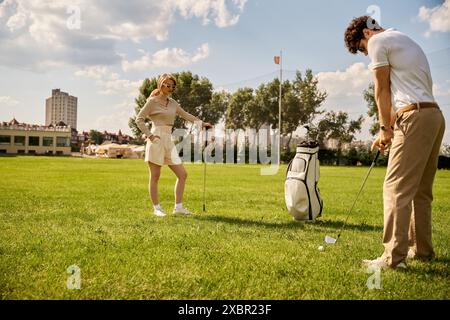 Ein stilvoller Mann und eine stilvolle Frau genießen eine Partie Golf auf einem wunderschönen grünen Golfplatz, umgeben von Natur und frischer Luft. Stockfoto
