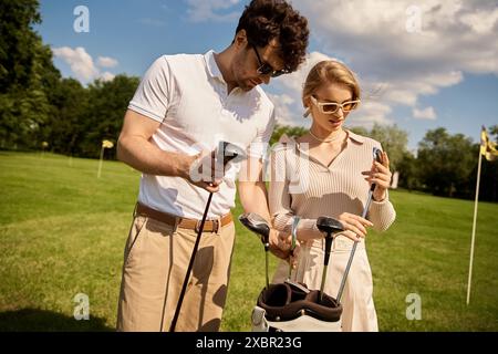 Ein junges Paar in eleganter Kleidung, das eine Runde Golf auf einem üppigen grünen Feld in einem renommierten Golfclub genießt. Stockfoto