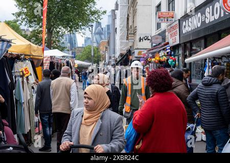 Straßenszene am Whitechapel Market in der Whitechapel High Street am 12. Juni 2023 in London, Großbritannien. Whitechapel ist ein ethnisch vielfältiges und lebhaftes Viertel im East End, in dem eine bedeutende Bevölkerung von Bangladeschen lebt. Das kann man entlang der Bürgersteige sehen, wo der Whitechapel Market und die umliegenden Geschäfte mit dieser wahrhaft multikulturellen Gesellschaft interagieren. Stockfoto