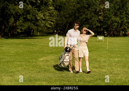 Ein stilvolles junges Paar macht einen gemütlichen Spaziergang auf einem malerischen Golfplatz und genießt die Gesellschaft der anderen. Stockfoto