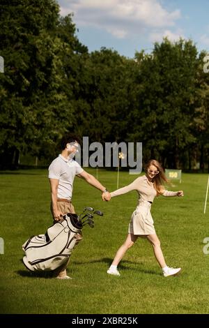 Ein stilvolles Paar in eleganter Kleidung hält Hände, während es gemütlich auf einem gepflegten Golfplatz spaziert. Stockfoto