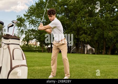 Ein Mann schlägt elegant einen Golfball mit einer Golftasche auf einem grünen Feld, umgeben von einem gehobenen Lebensstil. Stockfoto