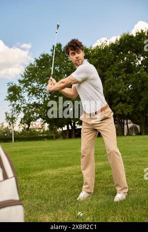 Ein junger Mann in eleganter Kleidung schwingt einen Golfschläger auf einem grünen Feld, verkörpert den gehobenen Lebensstil des alten Geldes. Stockfoto