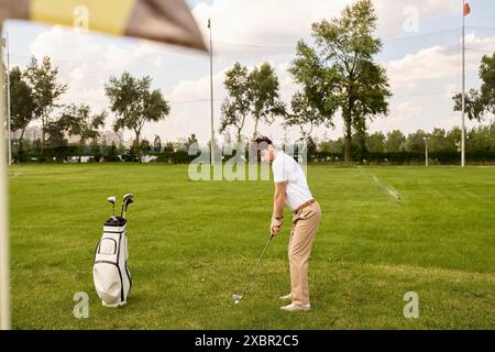 Ein Mann in eleganter Kleidung schlägt einen Golfball auf einem üppigen grünen Feld und zeigt Anmut und Raffinesse im alten Geldstil. Stockfoto