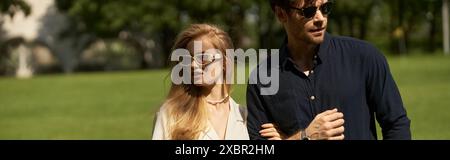 Ein schönes junges Paar, elegant gekleidet, spazieren zusammen in einem grünen Park. Stockfoto