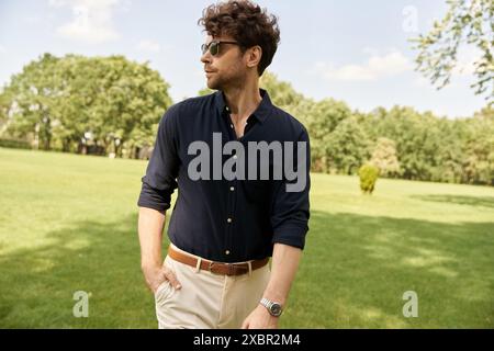 Ein Mann in blauem Hemd und brauner Hose spaziert friedlich durch einen Park, umgeben von Grün und Naturschönheiten. Stockfoto