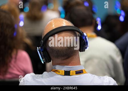 Die Teilnehmer auf der Messe hören den Hauptredner auf den Kopfhörern Stockfoto