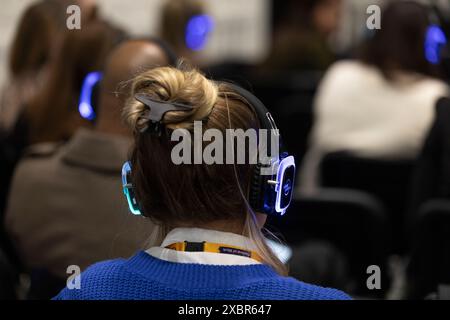 Die Teilnehmer auf der Messe hören den Hauptredner auf den Kopfhörern Stockfoto