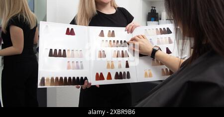 Eine Frau, die im Friseursalon Farbhaare aus der Palette wählt. Nahaufnahme einer Palette verschiedener Farben zum Färben im Friseursalon. Stockfoto