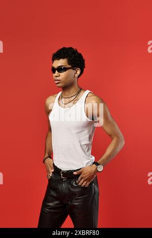 Hübscher afroamerikanischer Mann in stilvoller Sonnenbrille, mit weißem Tanktop und Lederhosen. Stockfoto