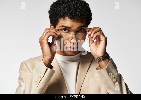 Junger Mann im braunen Anzug, der eine stilvolle Brille anzieht. Stockfoto