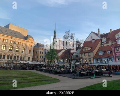 Riga, Lettland, 2. Mai 2024: Essbereich im Freien am Livu-Platz im Stadtzentrum von Riga. Am frühen Abend wird es von Feenlichtern beleuchtet. Historischer Platz Stockfoto