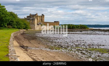 Das zerklüftete Blackness Castle hebt sich vor der dramatischen Küstenkulisse des Firth of Forth ab, der die Küstennäherungen bewacht. Stockfoto