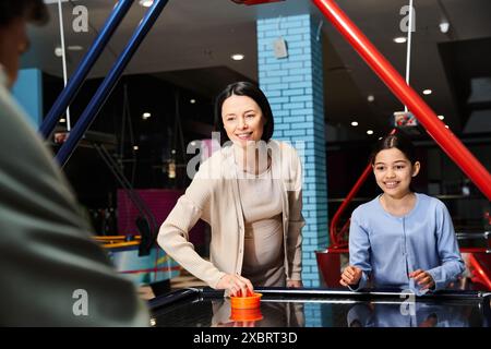 Eine lebhafte Familie genießt am Wochenende ein kompetitives Air-Hockey-Spiel in einer belebten Mall-Spielzone. Stockfoto