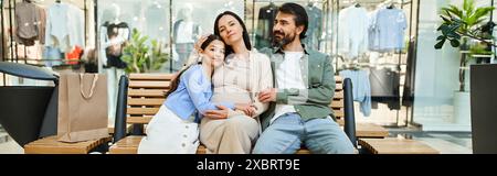 Ein Mann und eine Frau entspannen sich auf einer Bank mit Kind in einem geschäftigen Einkaufszentrum und machen eine Pause von ihrem Einkaufsausflug. Stockfoto