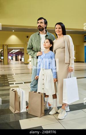 Eine fröhliche Familie mit Einkaufstaschen genießt einen Wochenendausflug in einem geschäftigen Einkaufszentrum, die Geschäfte zu erkunden und gemeinsam Einkäufe zu tätigen. Stockfoto