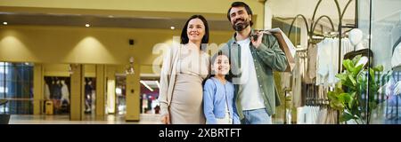 Eine fröhliche Familie genießt ein Einkaufswochenende, während sie gemeinsam durch ein geschäftiges Einkaufszentrum spazieren. Stockfoto