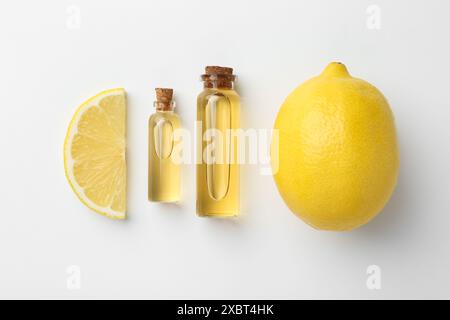 Flaschen mit ätherischen Ölen und Zitrone auf weißem Hintergrund, Draufsicht Stockfoto