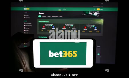 Person, die ein Mobiltelefon mit dem Logo des britischen Sportwettenunternehmens Bet365 vor der Business-Website hält. Schwerpunkt auf dem Display des Telefons. Stockfoto
