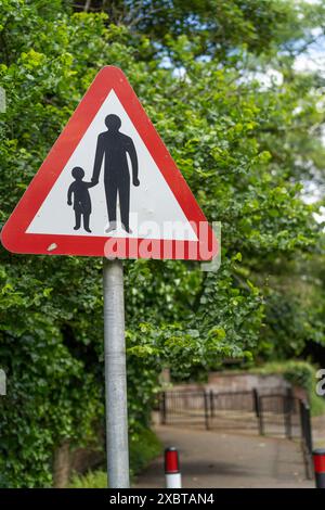 Nahaufnahme eines warnenden Fußgängerschilds in der Nähe eines Schuleingangs. Stockfoto