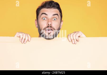Informationskonzept. Überraschter Mann mit leerem Schild. Demonstrieren des Kopierraums für Text oder Design. Staunender, aufgeregter Mann mit leerer Werbung Stockfoto