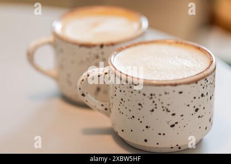 Zwei Tassen Cappuccino-Kaffeestation auf weißem Tisch, Nahaufnahme mit selektivem Weichfokus Stockfoto