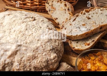 Brot mit Kleie, Nüssen und Rosinen auf einem Holzbrett vor dem Hintergrund eines Korbkorbs. Ausgewählter Fokus. Hochwertige Fotos Stockfoto