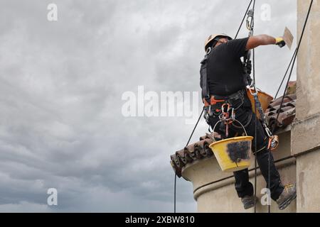 Akrobatik-Seilbau-Angestellter, der mitten in der Luft steht und an einer Fassade arbeitet. Stockfoto