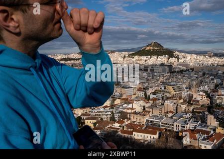 Ein Tourist im Vordergrund mit Blick auf den Lycabettos-Hügel oder Lykavittos von der Akropolis in Athen, der Hauptstadt Griechenlands am 11. Januar 2023. Touriste au Stockfoto