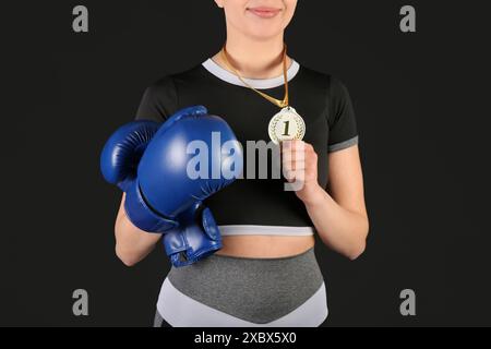 Weibliche Boxerin mit 1. Platz Medaille auf schwarzem Hintergrund, Nahaufnahme Stockfoto