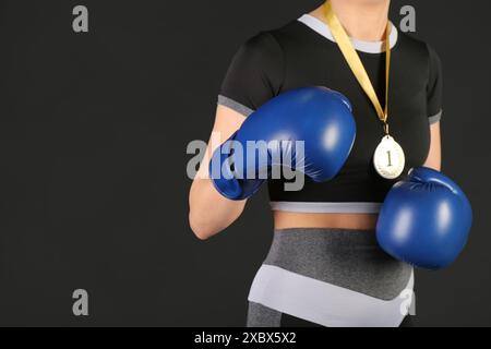 Weibliche Boxerin mit 1. Platz Medaille auf schwarzem Hintergrund, Nahaufnahme Stockfoto