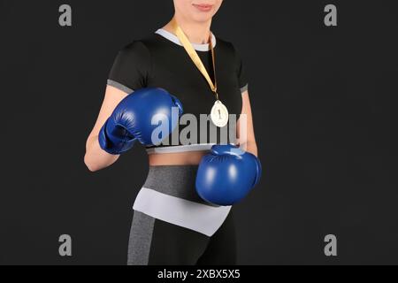 Weibliche Boxerin mit 1. Platz Medaille auf schwarzem Hintergrund Stockfoto