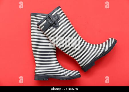 Stylische Gummistiefel auf rotem Hintergrund Stockfoto