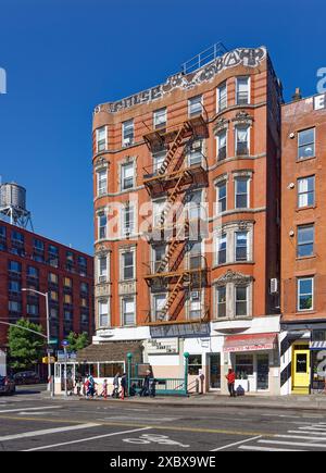 Kunstvoll verzierte Terrakotta-Spandrels und Fenster zieren dieses mittelhohe Apartment-Gebäude aus rotem Backstein in der Lower East Side von New York City. Stockfoto