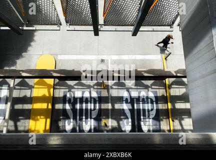 Blick von oben auf eine Frau, die an einer Parkgarage in Santa Monica, Kalifornien, USA, vorbeiläuft, mit dem Wort „STOP“ auf dem Boden und gelben Säulen Stockfoto