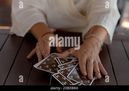 Eine Frau in einem leichten Outfit liest Tarotkarten auf einem Tisch in einem Café Stockfoto