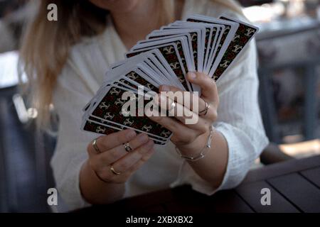 Eine Frau in einem leichten Outfit liest Tarotkarten auf einem Tisch in einem Café Stockfoto