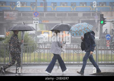 KIEW, UKRAINE - 12. JUNI 2024 - Fußgänger laufen unter Regenschirmen bei starkem Regen, der die Hälfte des Monatsdurchschnitts entsprach, Kiew, Hauptstadt der Ukraine. Stockfoto