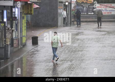 KIEW, UKRAINE - 12. JUNI 2024 - Ein Mann läuft unter starkem Regen, der die Hälfte des monatlichen Durchschnitts beträgt, Kiew, Hauptstadt der Ukraine. Stockfoto