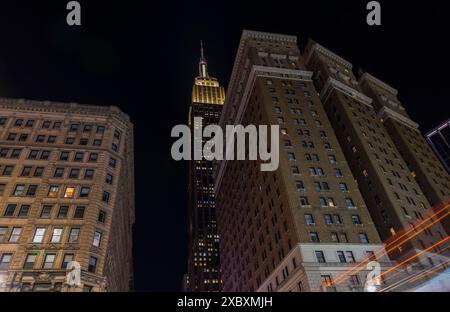 Die Nacht fällt über Manhattan, mit dem beleuchteten Turm des Empire State Building, der seine strahlende Präsenz über einem von Türmen dominierten Stadtbild ausstrahlt Stockfoto