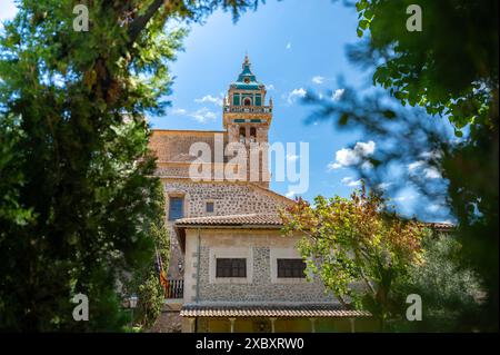 Kirchturm Iglesia de la Cartuja, Valldemossa, Mallorca, an sonnigem Tag mit Bäumen davor, horizontaler Schuss, Mallorca Stockfoto