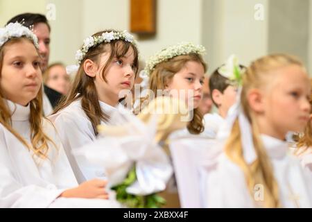 Kinder in Bänken bei ihrer ersten Kommunionmesse. Stockfoto