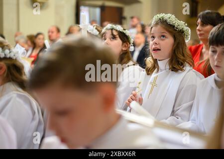 Kinder in Bänken bei ihrer ersten Kommunionmesse. Stockfoto