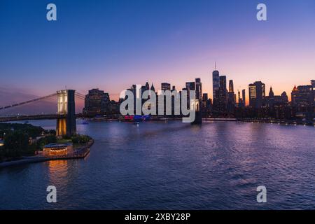Brooklyn Bridge und New York Skyline über den East River bei intensivem Sonnenuntergang. Stockfoto